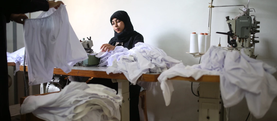 Young female employee carefully sewing men's underwear.
